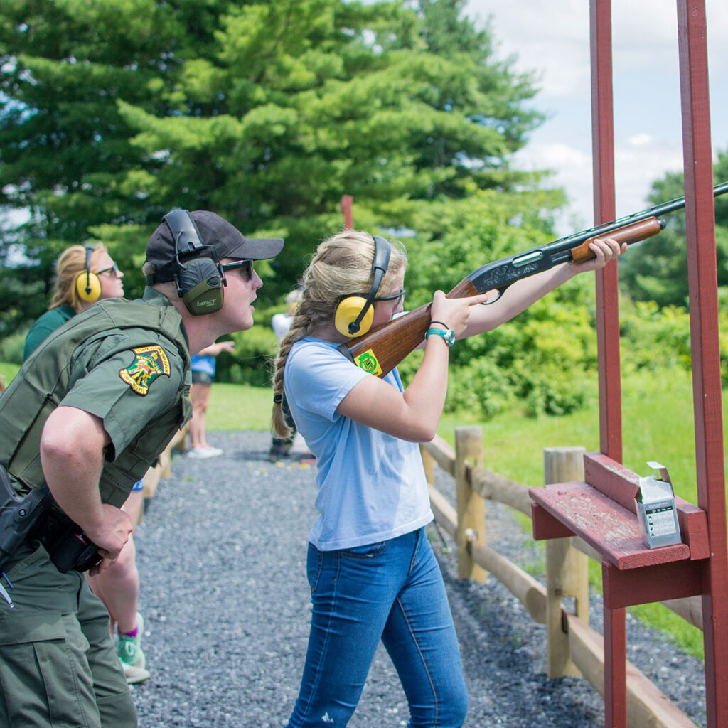 A child firing a shotgun under supervision from a Vermont game warden