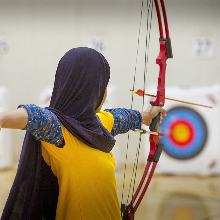 A girl in hijab shooting a bow