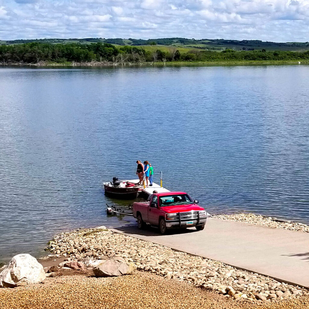 Three people launching a boat at a boat ramp