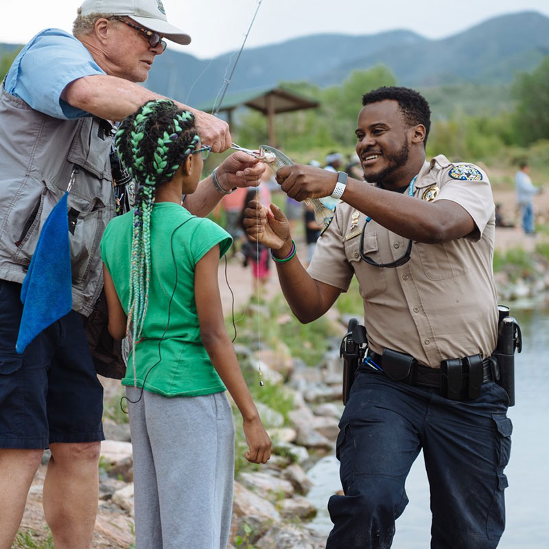 A Colorado Parks and Wildlife employee helping people unhook a fish