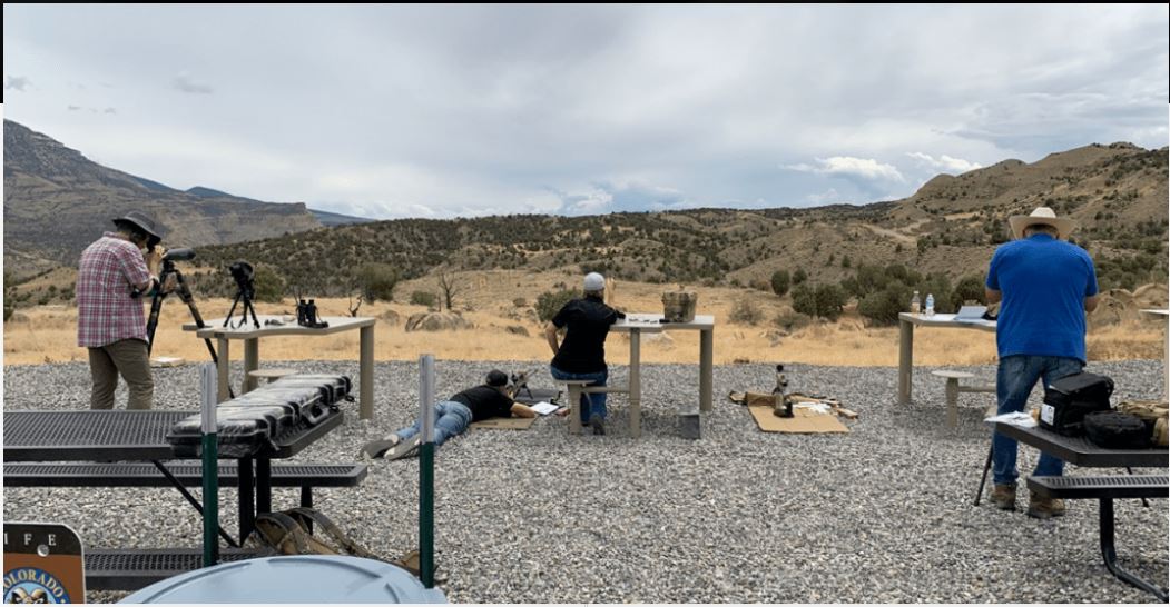 Three people at a target range outdoors