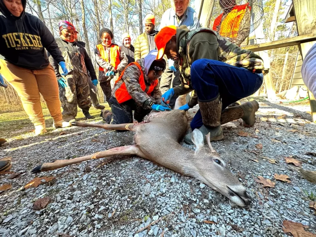 Sgt. Freeman and university students inspect a harvested deer during a mentor hunting opportunity.