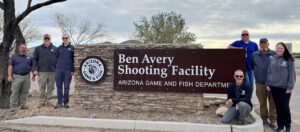 Arizona Game and Fish staff stand by the Ben Avery Shooting Facility sign.