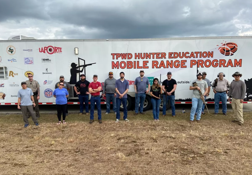 Purtis Creek Waterfowl 101 Program shooting sport youth participants and mentors stand in front of the Hunter Education Mobile Range.