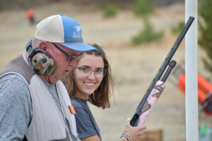 female trap shooter smiling at her coach