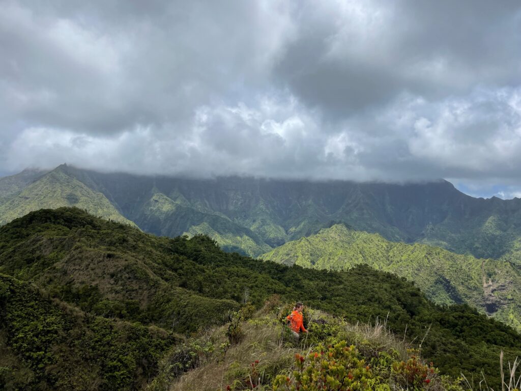 Game mammal survey researcher hikes rough terrain to place game cameras on ridge peaks.