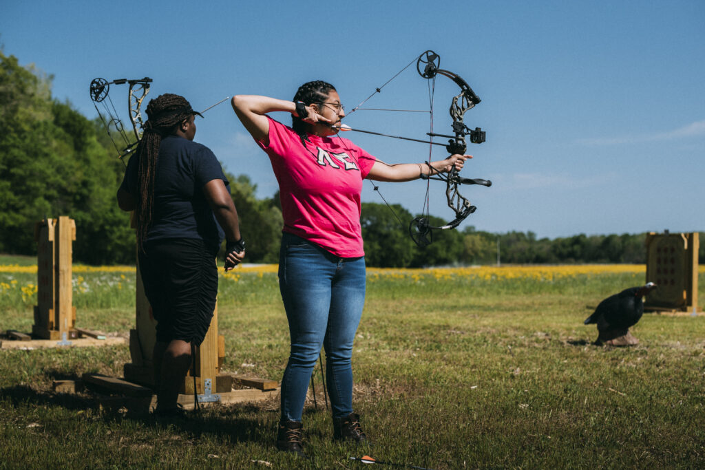 Archery target shooter aims at target on an outdoor range.