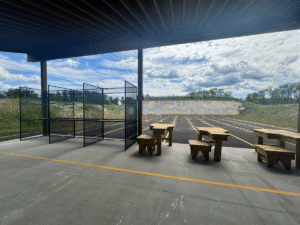 Empty firing line shows updated wooden shooting benches and range berm in the background