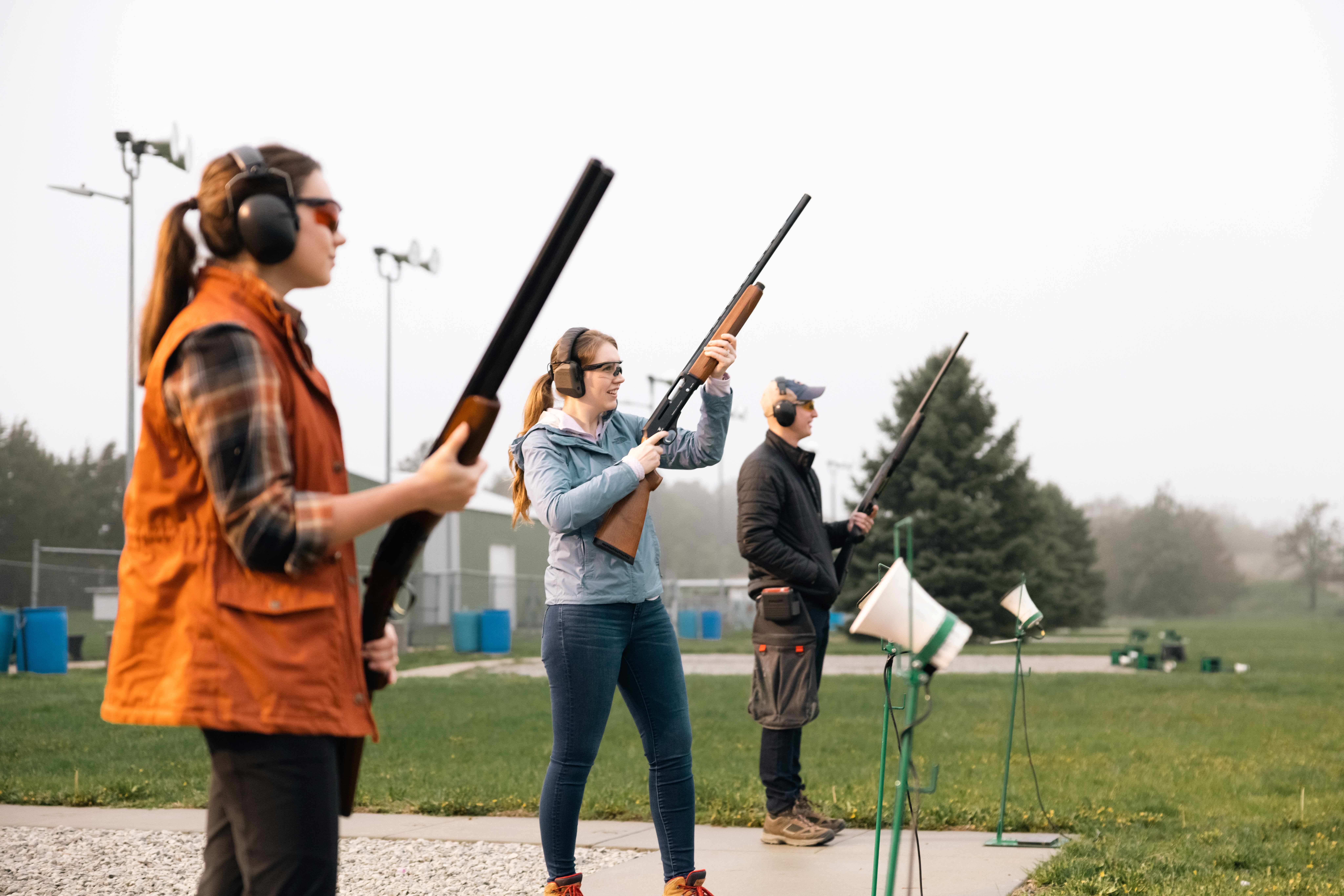 Target shooters stand at a range shooting line awaiting targets.