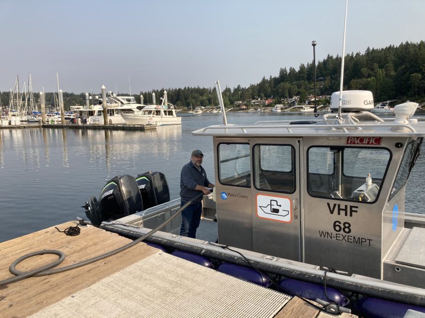 Man standing on a pumpout station vessel, smiling at the camera