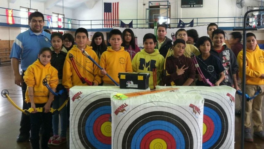 Group of youth archers in a school gymnasium